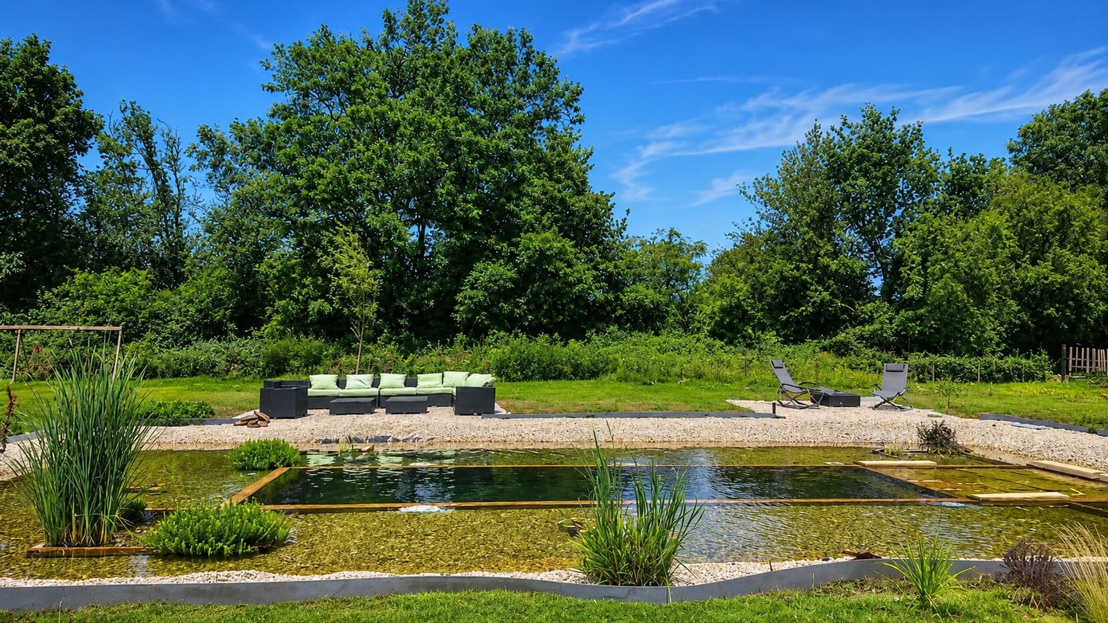 Avondlicht over de vijver en tuin van het domein in Lison