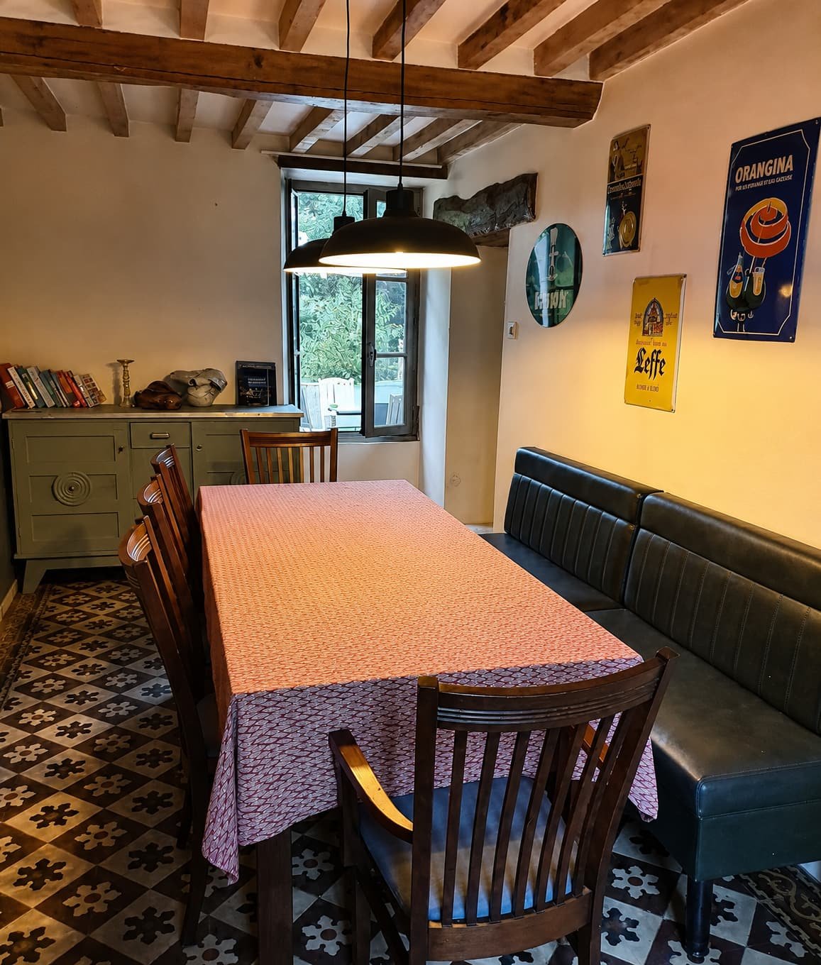Lange eettafel met bank langs de muur, onder een tegelvloer met patroon