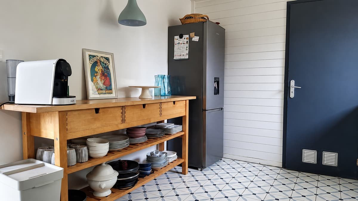 Keuken met blauw geschilderde kasten, houten blad en een fornuis onder het raam