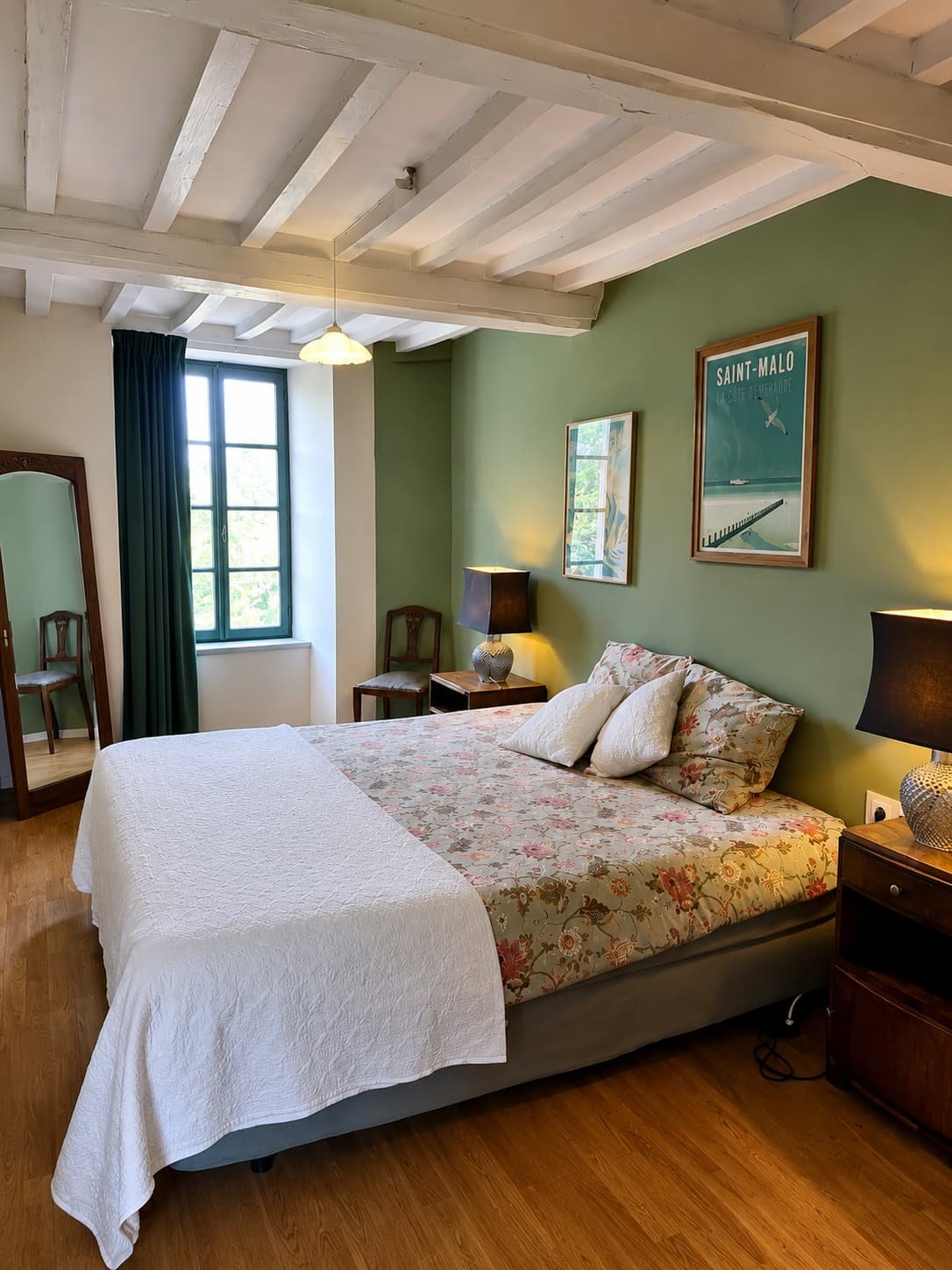 Slaapkamer met olijfgroene wand, spiegel en een affiche van Saint-Malo