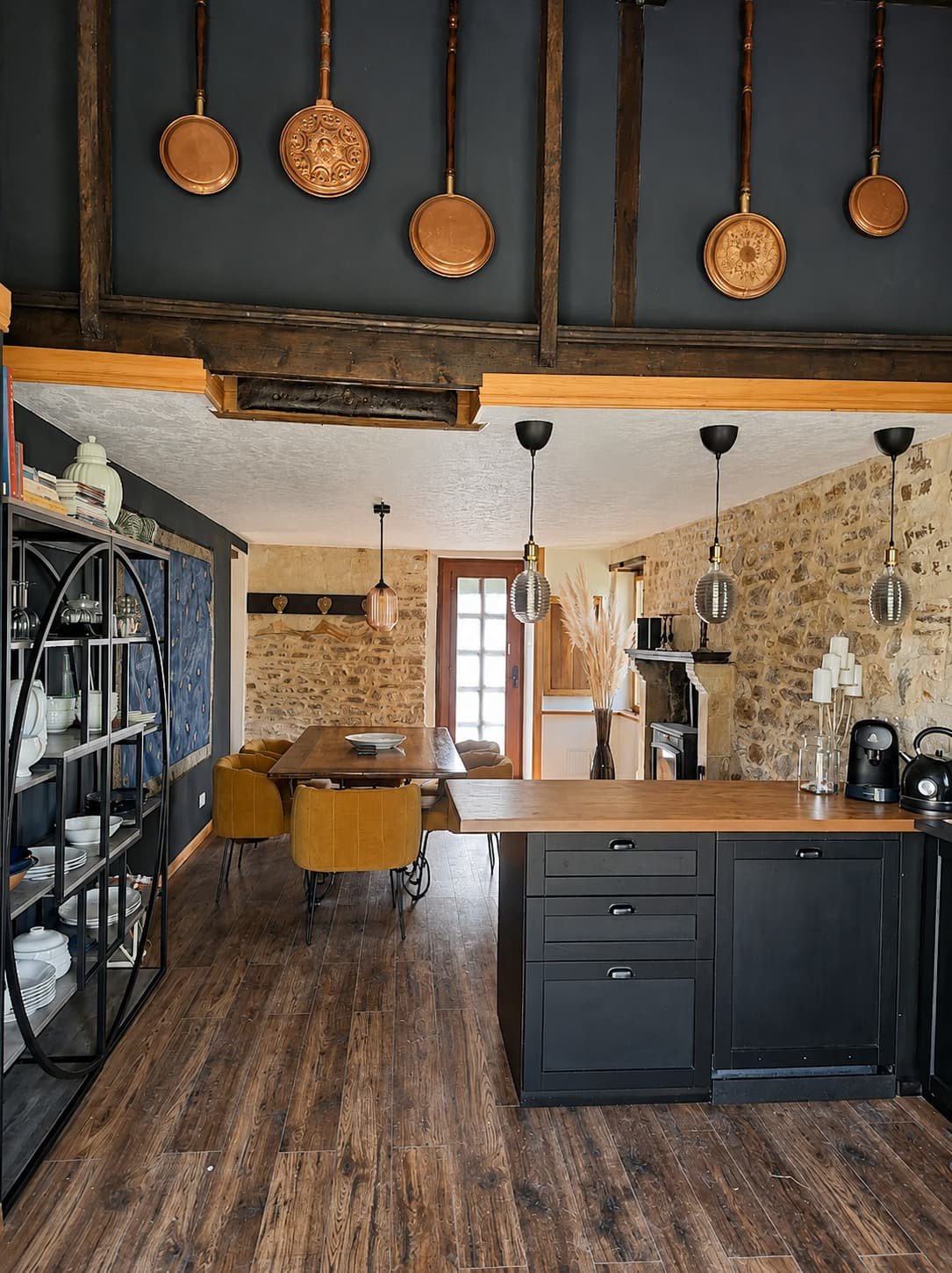 Open keuken en eetkamer onder een balkenplafond, met hanglampen boven de tafel