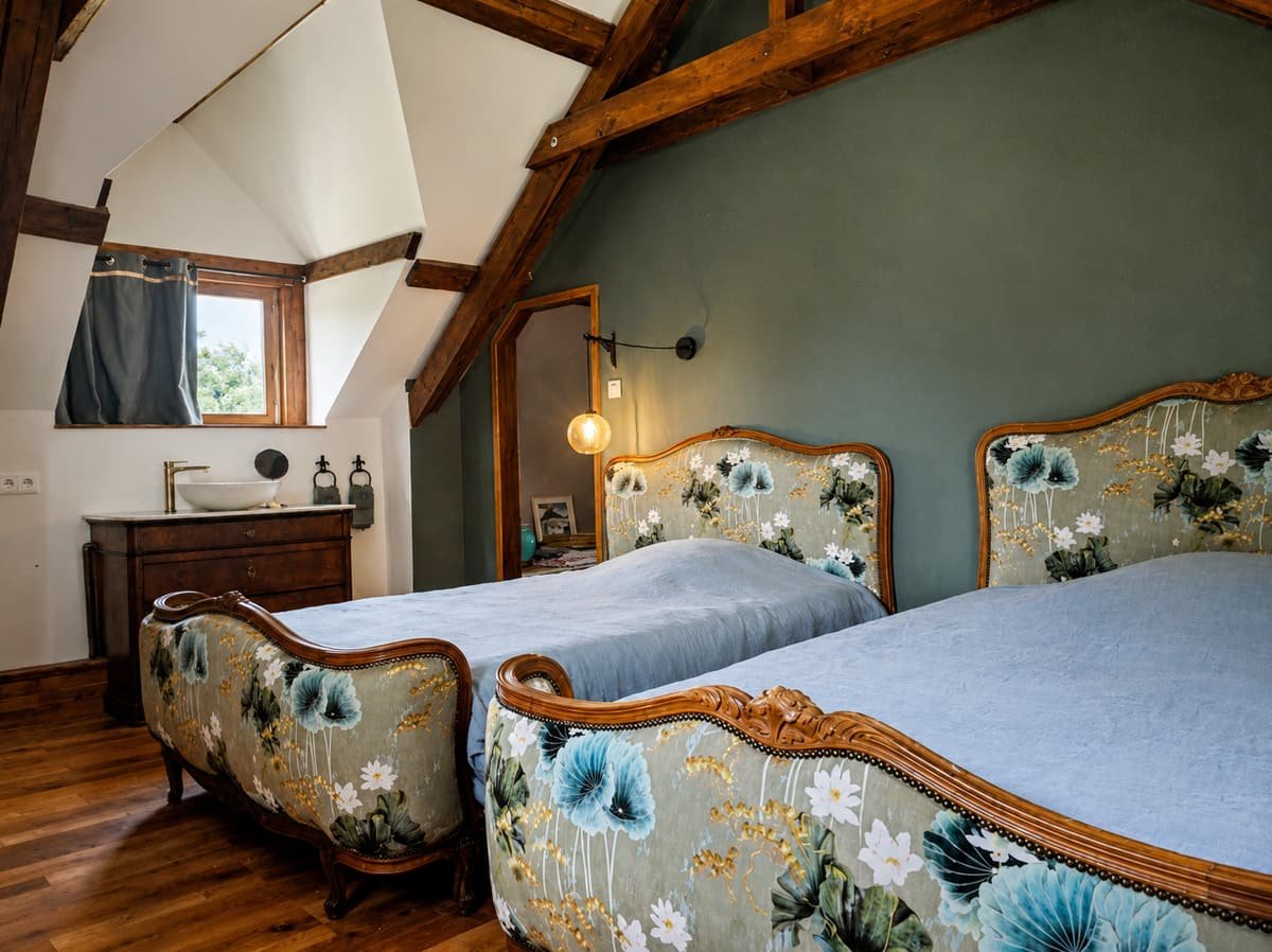 Slaapkamer met twee antieke bedden met bloemenstof onder een balkenplafond