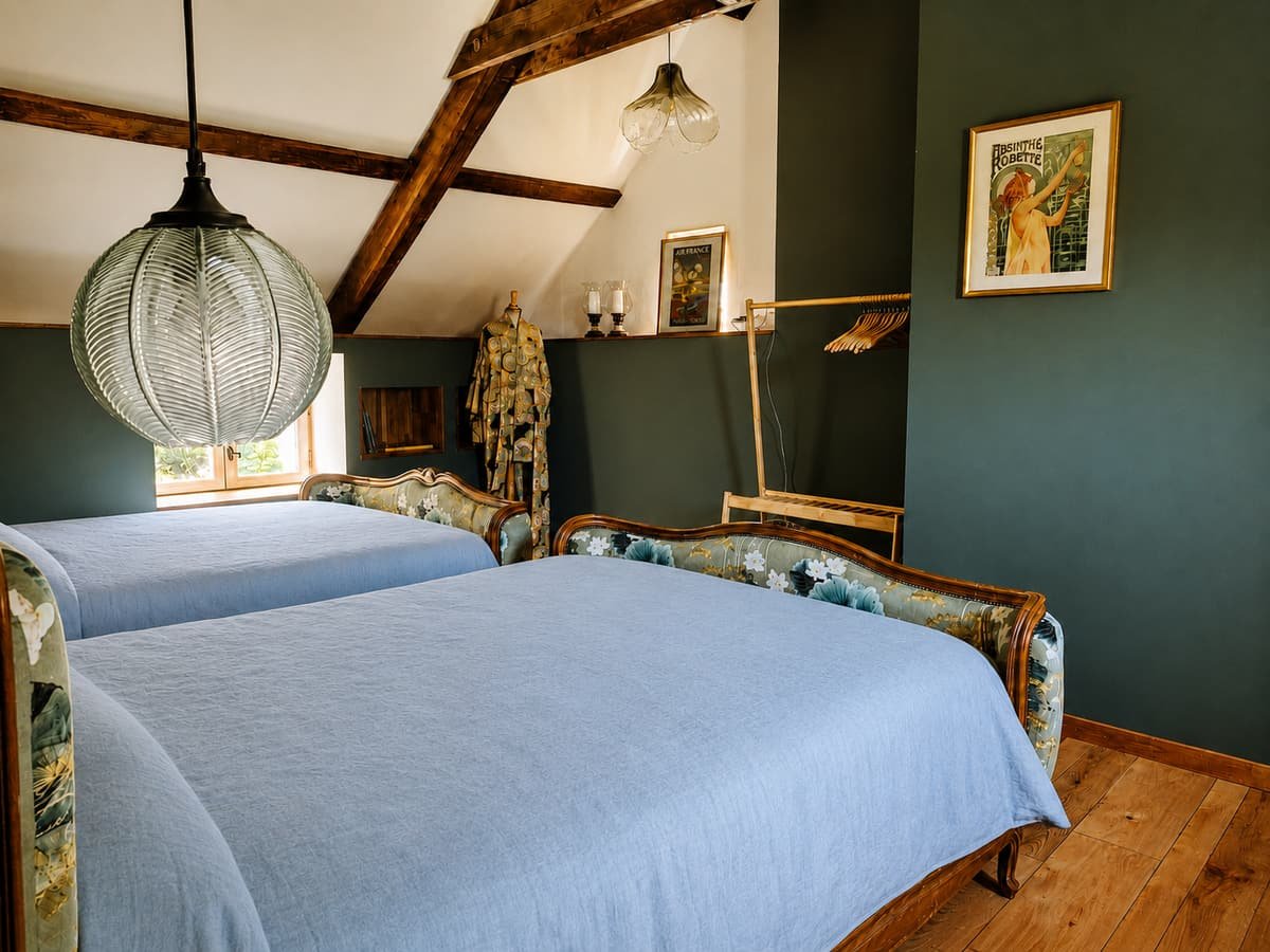 Twee bedden naast elkaar onder een bollamp, met een groene wand erachter