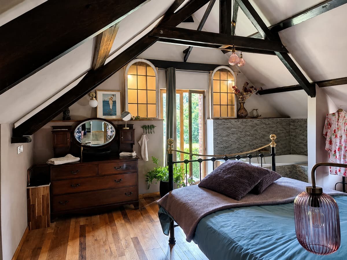 Slaapkamer met antieke commode, ovale spiegel en boogramen