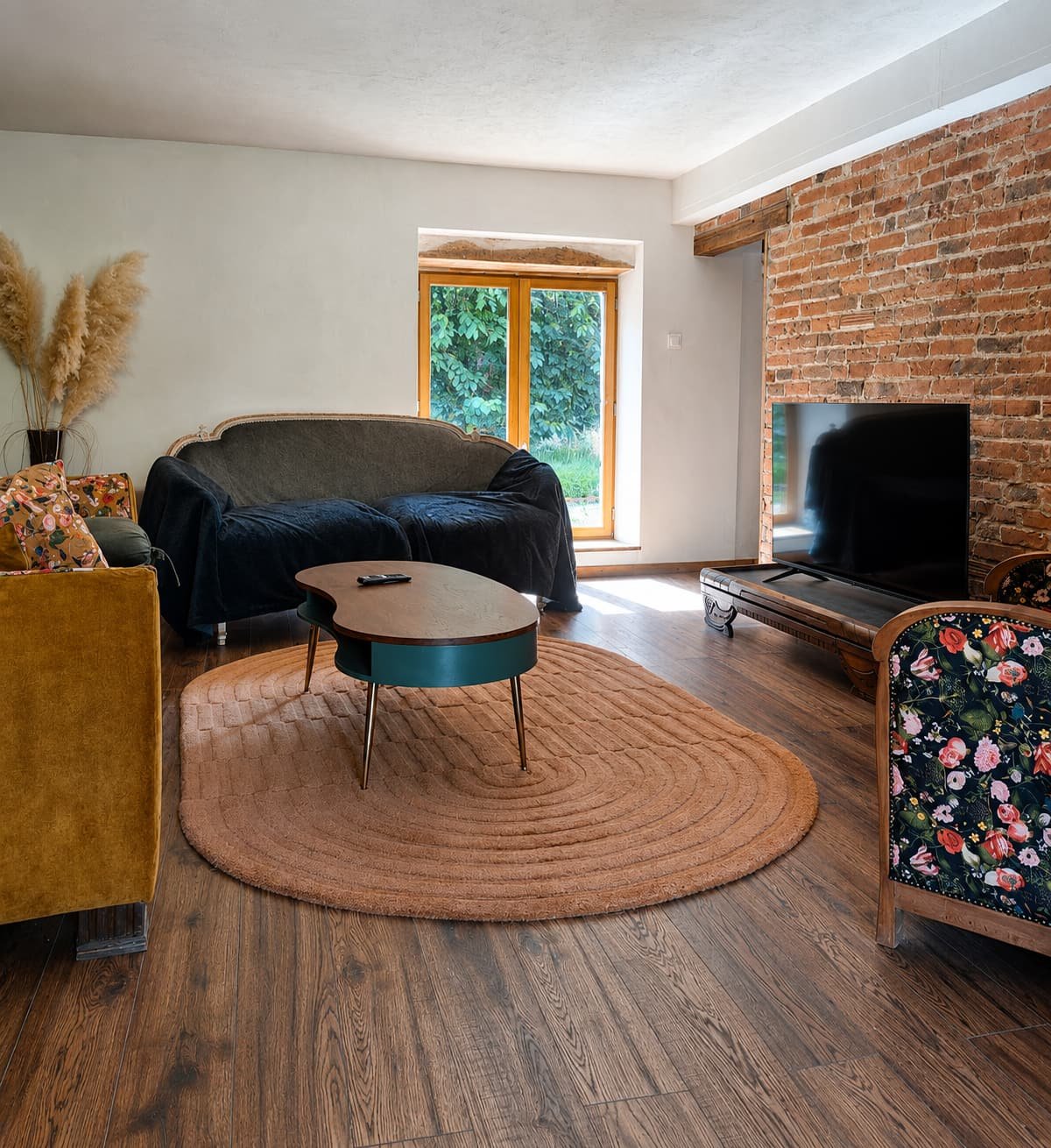 Zitkamer met leren bank, rond vloerkleed en pampasgras bij het raam