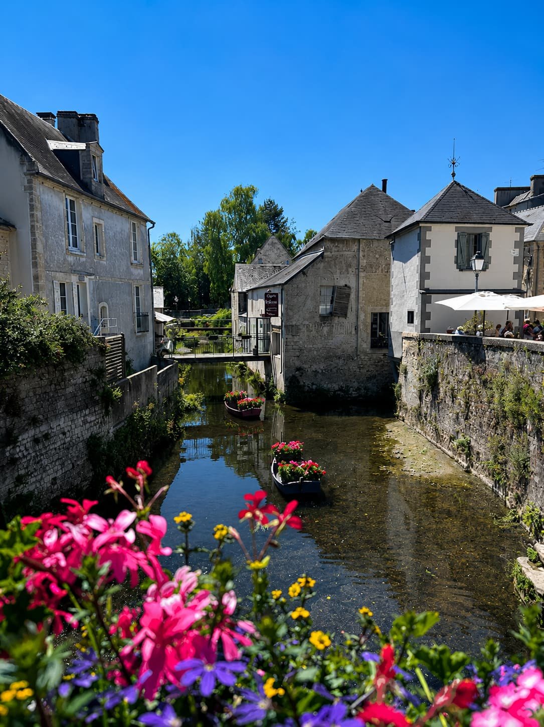 Old houses along the water in Bayeux, with flower boxes on the quay